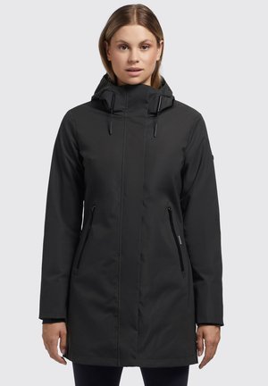 Veste noire imperméable avec capuche, zippers sur les poches latérales, design épuré et texture lisse. Mi-longue avec une coupe droite.