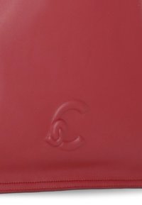 Borsa in pelle rossa con logo impresso, texture liscia e cuciture sottili lungo i bordi. Design minimalista senza ulteriori abbellimenti.