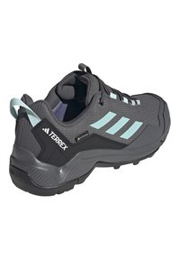 Svart og grå Adidas Terrex vandresko med lyseblå striper, snøringer og hælloop, har Gore-Tex og en robust såle.