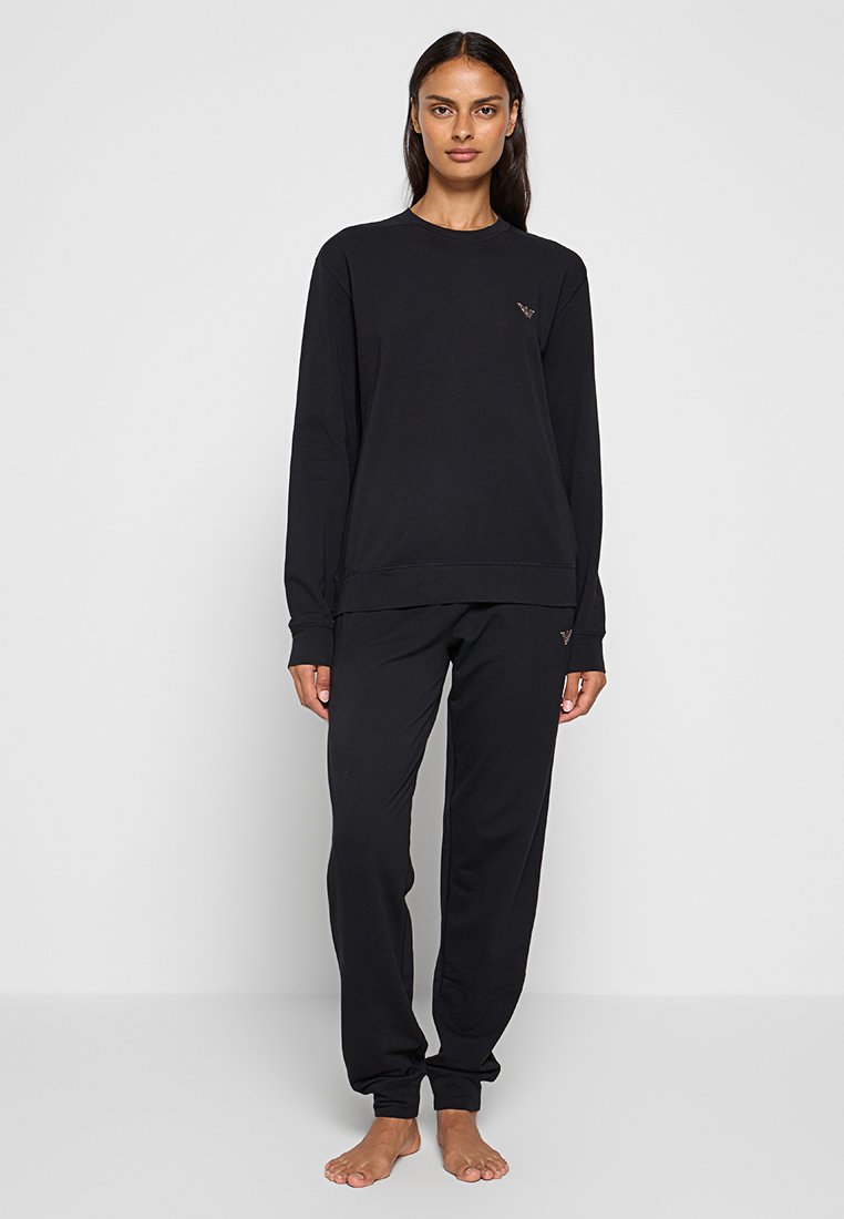 Set di felpa nera e pantaloni, realizzato in tessuto morbido. Presenta un collo arrotondato e un design loose-fit con un discreto dettaglio del logo.