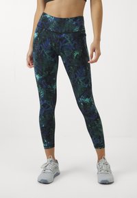 Leggings a vita alta in verde scuro con motivo floreale blu, realizzati in tessuto traspirante e con un design aderente, abbinati a scarpe da ginnastica grigie.