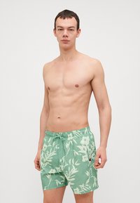 Grüne Badehose mit einem weißen Blumenmuster, Zugbandbund und Seitentasche. Leichter Stoff mit bequemer Passform.