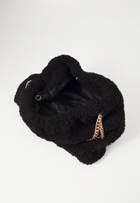 Black furry handbag with a soft texture, gold chain accents, and a smooth interior lining. The bag has a scrunched design and an open top.