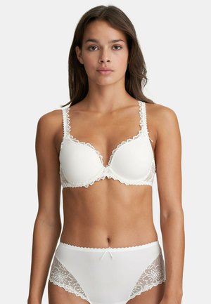Reggiseno bianco con bordature in pizzo, coppe imbottite e spalline regolabili; slip bianchi coordinati con dettagli in pizzo floreale e un fiocco.