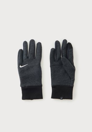 Ζευγάρι σκούρα γκρι γάντια Nike με μαύρες μανσέτες, συμβατά με οθόνες αφής άκρα δακτύλων και λογότυπα Nike swoosh σε λευκό στα χέρια και στην ετικέτα.