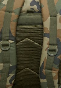 Kamuflāžas mugursoma ar mīkstu sietu aizmuguri, zaļām siksnām un regulējamiem sprādzēm. Redzama strukturēta virsma un kontrastējoši krāsu raksti.