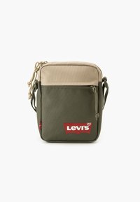 Žalia ir smėlio spalvos audinio petnešinė rankinė, turi priekinę kišenę su raudonu Levi's logotipu, raišteliu užsegama ir reguliuojamu dirželiu.