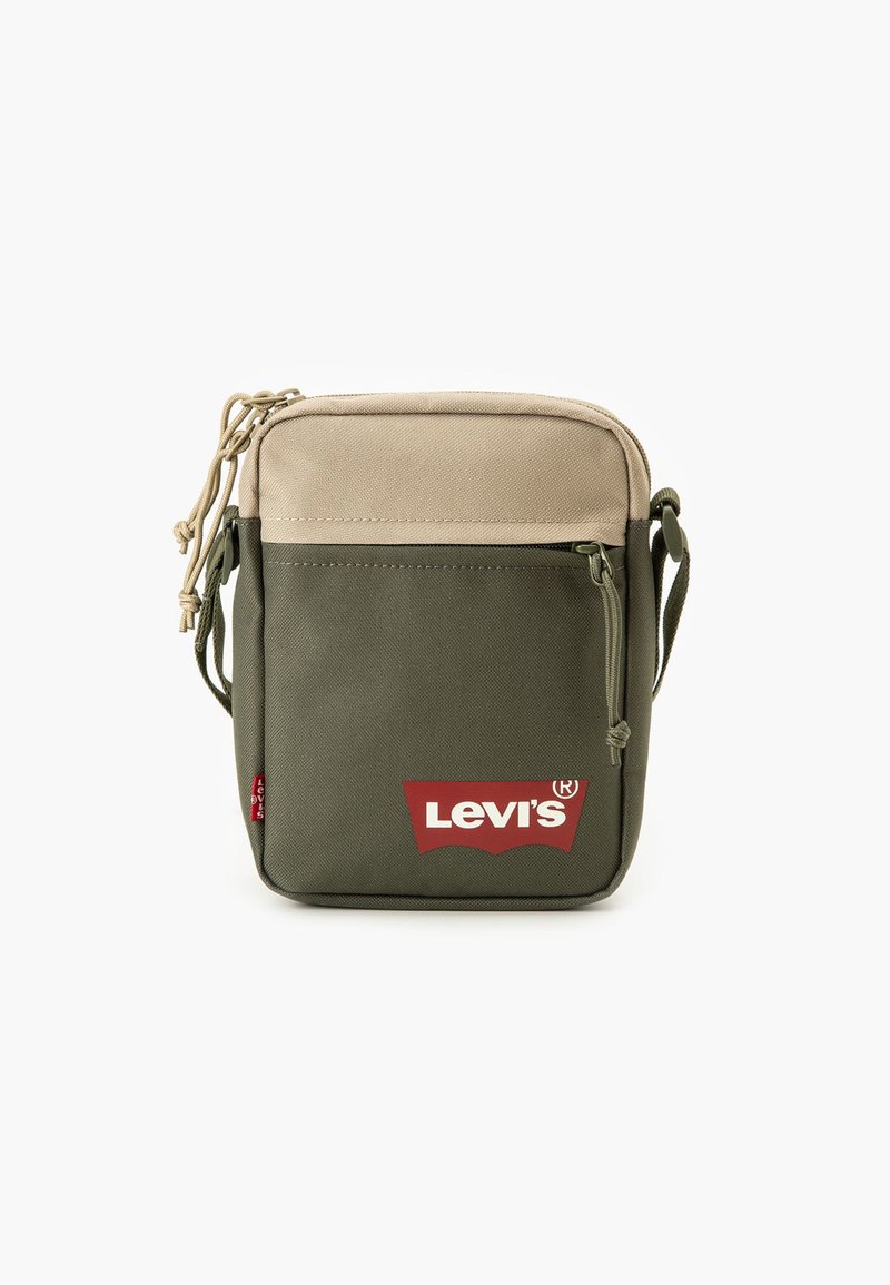 Žalia ir smėlio spalvos audinio petnešinė rankinė, turi priekinę kišenę su raudonu Levi's logotipu, raišteliu užsegama ir reguliuojamu dirželiu.