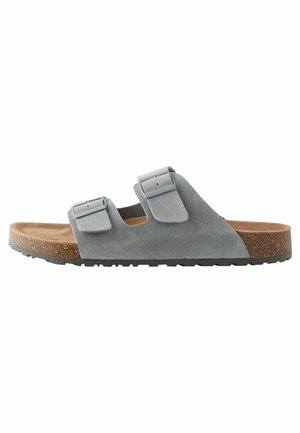 Gray suede sandals with two adjustable straps, cork midsole, and textured rubber outsole, featuring a minimalist design.
