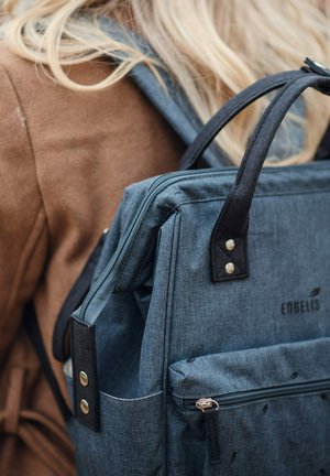 Grauer Stoffrucksack mit schwarzen Akzenten, Reißverschlussfächern und Muster. Mit robusten Griffen und Metallbeschlägen ausgestattet.