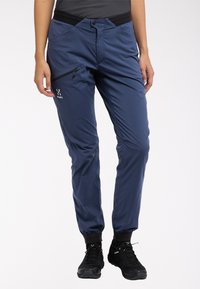 Marineblauwe waterdichte wandelpantalons met een slanke pasvorm, ritszak op de dij, elastische tailleband en elastische boorden voor een verstelbare pasvorm.