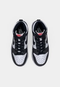 Nike tenisice s visokim gornjim dijelom u crno-bijelom kožnom dizajnu, s perforiranim vrhom, podstavom od teksturiranog materijala i crvenim detaljima na logotipu.