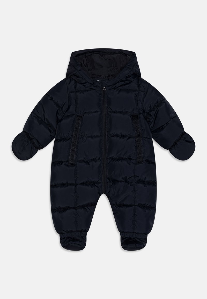 Námořnický modrý zateplený snowsuit s kapucí, předním zipem a elastickými manžetami. Hladká textura s vertikálním prošíváním. Dvě přední kapsy.