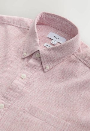 Vaaleanpunainen nappipaita, jossa on tekstuuri ja rintatasku. Paidassa on valkoiset napit ja kauluksen sisäpuolella tunnisteet.