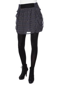 Falda corta negra y estampada con detalles plisados y una cinturilla ancha, combinada con medias negras y botas de tobillo con cordones.