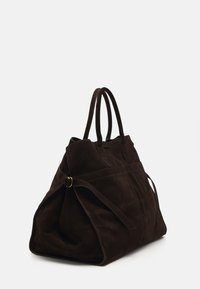 Sac fourre-tout en daim marron avec deux poignées, design spacieux, sangles latérales et d étails de coutures visibles. Texture douce avec une forme structurée.