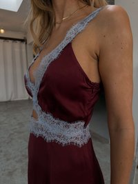Burgundy satin sleepwear with light blue lace trim along the neckline and waist, featuring cut-out detail and smooth, glossy texture.
