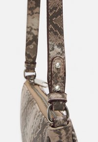 Borsa con motivo a pelle di serpente con una base color avana. Presenta una tracolla testurizzata, dettagli in metallo argentato e una chiusura con zip.