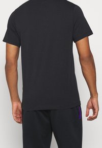 Camiseta negra de manga corta con cuello redondo, fabricada en suave algodón. El dobladillo es recto y tiene un corte relajado.