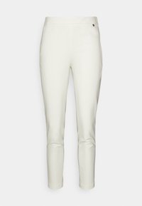 Białe dopasowane spodnie o gładkiej fakturze, wąskie, sięgające kostek, z zapięciem na guzik z przodu. Posiadają subtelne logo marki.
