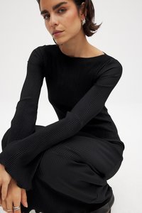 Abito nero a coste con maniche lunghe, caratterizzato da una silhouette aderente e polsini svasati, realizzato in un tessuto testurizzato. Finitura liscia e monocromatica.