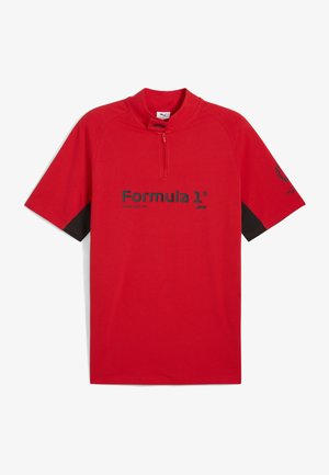 Röd t-shirt med kort ärm och halvdragkedja. Har svarta detaljer på ärmarna och "Formula 1"-logotypen i svart på framsidan. Tillverkad av bomull.