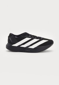 Scarpa da corsa nera Adidas con tre strisce bianche sul lato e suola spessa con la scritta Lightstrike Pro, vista dall’esterno.
