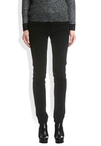 Jean skinny noir avec une texture lisse, dotés d'une taille mi-haute, de poches avant et d'une coupe slim. Portés avec des chaussures noires.
