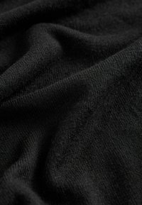 Tissu tricoté noir avec une surface douce et texturée, mettant en valeur de subtiles variations dans le tissage et la profondeur. Drapeau fluide sans motifs visibles.