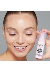 NYX Marsh Mellow Primer in a pink bottle with a pump dispenser, held in one hand. The label features black text on a white background.