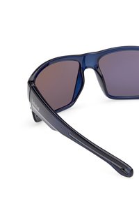 Granatowe plastikowe okulary przeciwsłoneczne z ciemnymi gradientowymi soczewkami, elegancki design i logo na ramieniu. Posiadają matowe wykończenie i wygięte zauszniki.