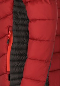 Rød pufferjakke med sort inderside. Har en lynlåslomme i kontrasterende orange. Tekstureret quiltet design med isolering.