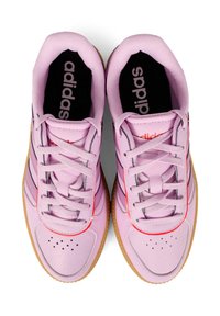 Jasnoróżowe buty sportowe z teksturowaną cholewką, pomarańczowymi akcentami i czarnymi wkładkami. Posiadają tradycyjne sznurowanie oraz gumowe podeszwy.
