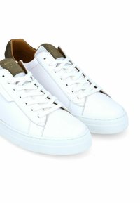 Baskets en cuir blanc avec une semelle plate en caoutchouc blanc. Les caractéristiques incluent des lacets blancs, des accents vert olive au talon et une texture lisse.