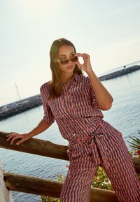 Pakket met gestreepte shirt en broek in koraal en marineblauw, met een geometrisch ontwerp, korte mouwen, een knoopsluiting aan de voorkant en een gestrikte taille.