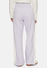 Lichtpaarse wijde broek van een textuurstof. Heeft een witte zijpaneel en een elastische tailleband voor comfort.