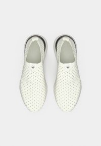 Chaussures blanches à enfiler avec une texture perforée, une doublure intérieure grise et une semelle noire. Dispose d'un patch logo sur le dessus.
