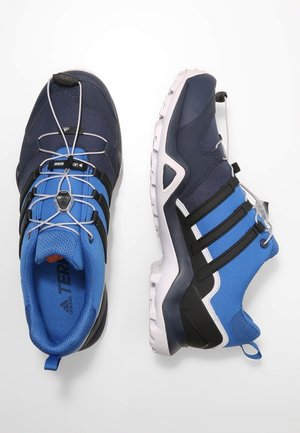 Niebiesko-czarne buty sportowe charakteryzują się siateczkową cholewką, elastycznymi sznurowadłami oraz białą podeszwą z czarnymi akcentami. Zaprojektowane do użytku na świeżym powietrzu.