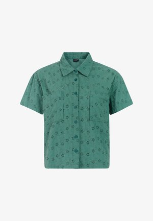 Kortärmelig overhemd van groen textuurstof, met een knoopsluiting aan de voorkant, twee borstzakken en een bloemmotief met uitgesneden patronen over het hele kledingstuk.