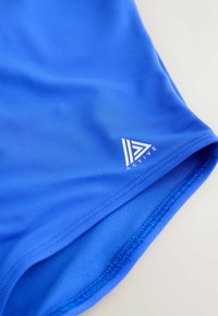 Modrá atletická tkanina s viditelným šitím a malým bílým trojúhelníkovým logem "Active" u lemu na světlém pozadí.