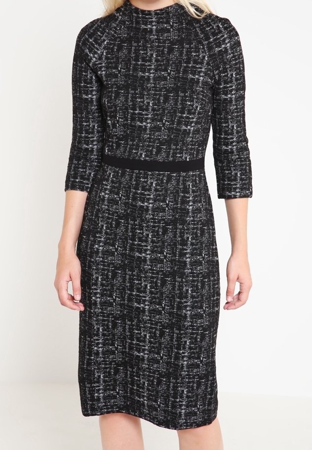 Svart och vit stickad klänning med ett strukturerat mönster, tre fjärdedelsärmar och en åtsittande midja, som faller till mitten av vaden.
