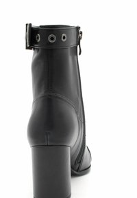 Czarne skórzane botki za kostkę z zamkiem po bokach, okrągłym czubkiem i grubym obcasem. Posiadają ozdobny pasek z metalowymi oczkami.