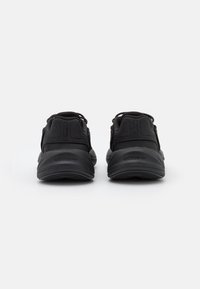 Scarpe sportive nere con una parte superiore in sintetico liscio, tallone imbottito e suola testurizzata. Presentano linguette per il sollevamento e un design minimalista.