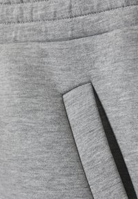 Zbliżenie na kieszeń z szarego materiału heather z pasującą klapą z tkaniny na odzieży.
