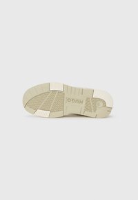Rubber sneaker outsole in beige and cream, featuring geometric tread patterns, cushioning elements, and raised accents for grip and durability.
