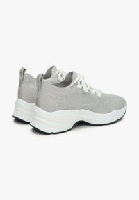 Jasnoszare, dziergane sneakersy mają teksturowaną cholewkę z białymi sznurowadłami, wyściełaną białą podeszwę środkową oraz czarne akcenty na podeszwie zewnętrznej.