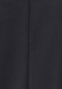 Detalle de la costura en tela negra que muestra una textura intensamente tejida y una línea de puntada vertical en el centro.