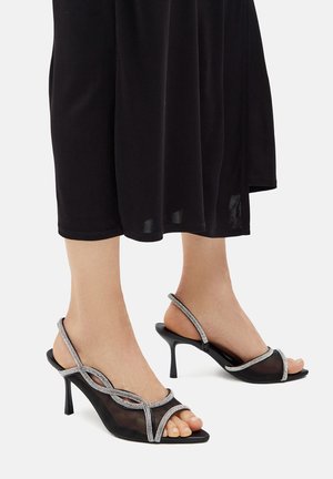 Sandale negre cu toc, cu parte superioară din plasă transparentă, având accente de strassuri argintii și curele subțiri la glezna, design cu vârf decupat și toc stiletto.