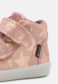 Rosa vanntett sko laget av skinnende stoff med stjernemønster, med borrelåsstropper og grå fôr. Inkluderer et lite Gore-Tex-merke.