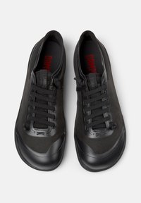 Sorte sneakers med en tekstureret overdel, glat gummitåspids og flade snørebånd. Har logo på pløsen og indersålen.